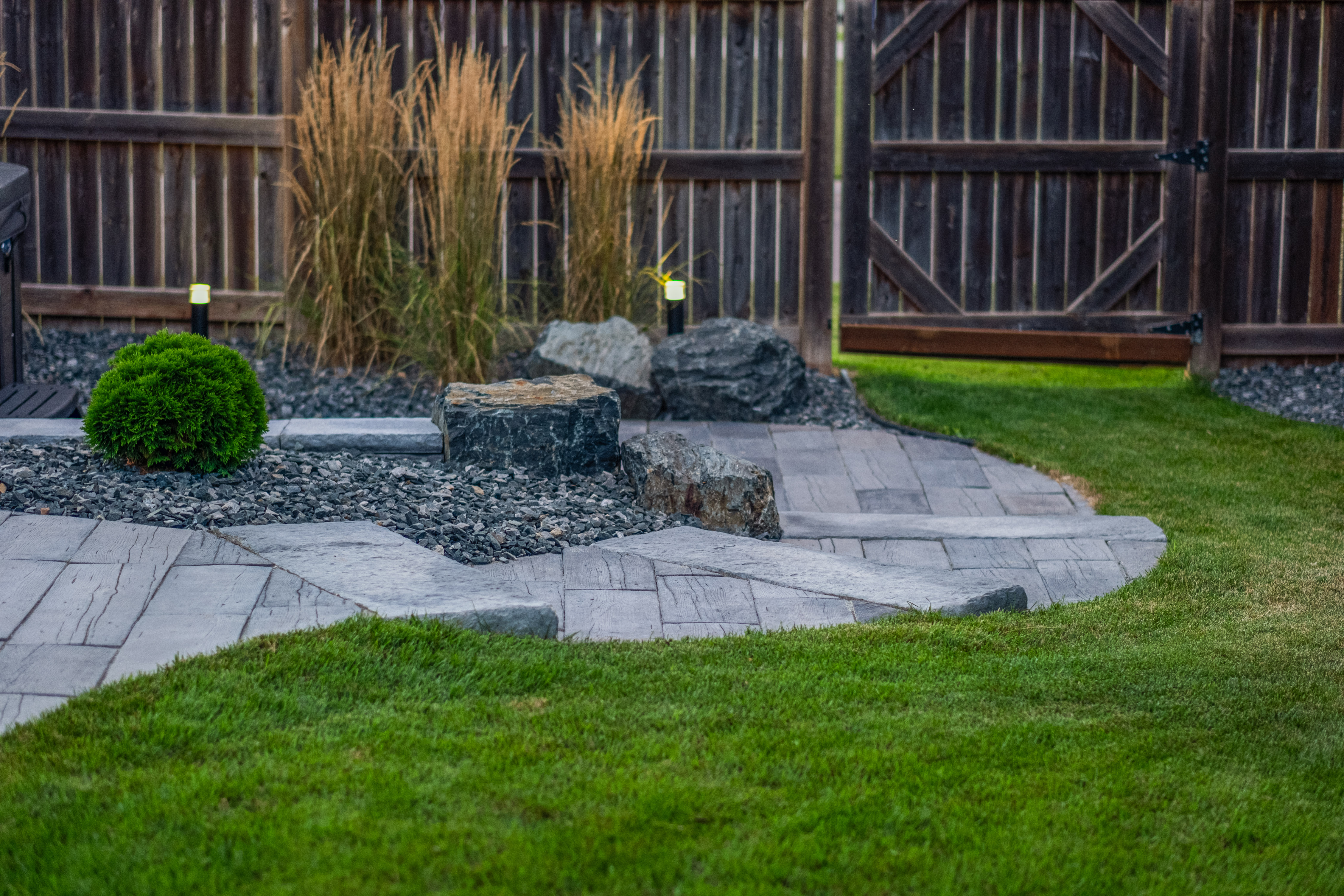 Stone edging and river rock accents alongside a paver patio in Michigan